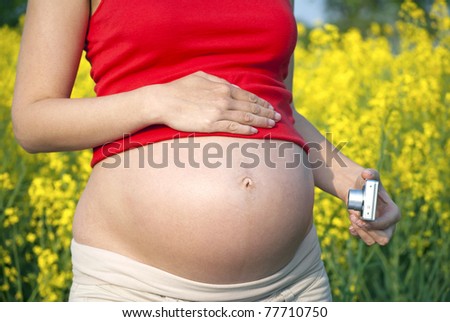 Pregnant woman taking picture of her growing bump