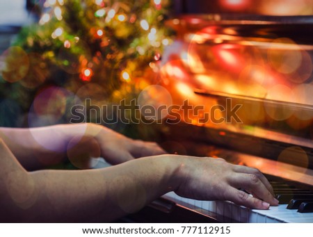 close up of man hands plays  on  Piano Keys with Christmas tree and decoration Bokeh light effected , in the night of Christmas season, Christmas background, copy space