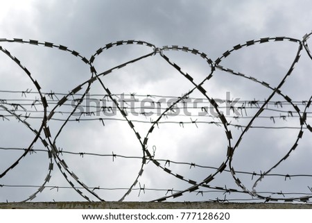 Barbed wire against a background of cloudy sky