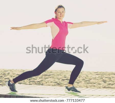 Smiling young woman training yoga poses on beach in sunny morning