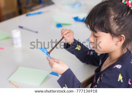 Selective Focus. The Adorable Little asian girl trying to making the card to gift to her parents.