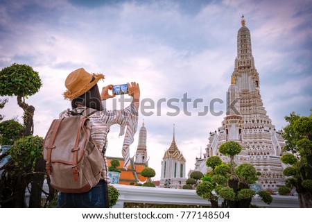 Asian woman tourists are taking photos With a smartphone at the Wat Arun temple on vacation Bangkok Thailand.