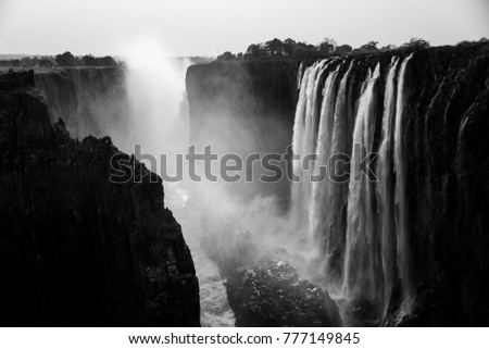scenic picture of the victoria falls black and white photographed with both sides of the canyon and steam all over it 