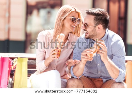 Young couple in love,guy and girl sitting and eating sandwich after shopping.