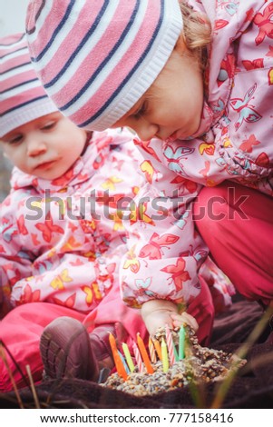 Portrait of two sisters of a little girl in a warm hat and warm clothes outdoors in an autumn day