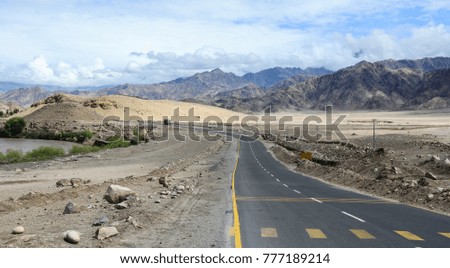 Cars run on mountain road at summer day in Ladakh, India.