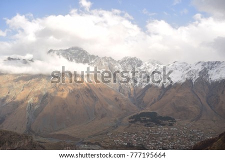 The mountains with snowy peaks and a small town at the foot.