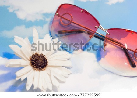 Bright summer composition. Travel or tourism concept. Pink sunglasses and a flower on a sky image background. Close up.
