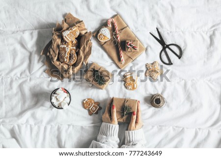 Woman wrapping beautiful vintage Christmas presents in bed
