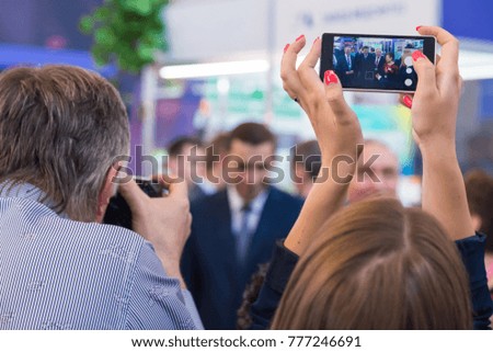 woman makes a photo on a smartphone at an exhibition