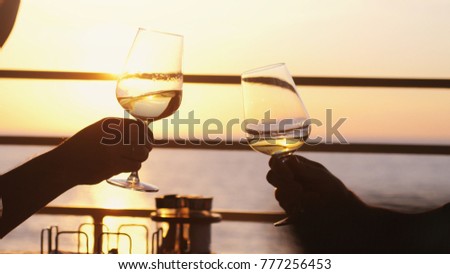 People holding glass of wine, making a toast over sunset. Party outdoors. Enjoying time together.