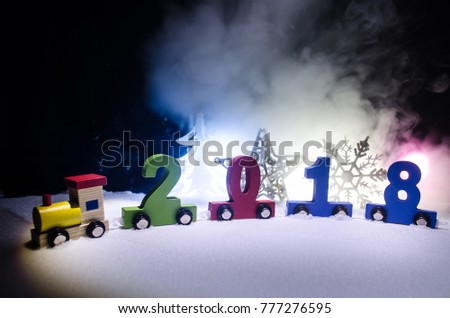 2018 happy new year, wooden toy train carrying numbers of 2018 year on snow. Toy train with 2018. Copy space. Christmas decoration. Selective focus. Dark background