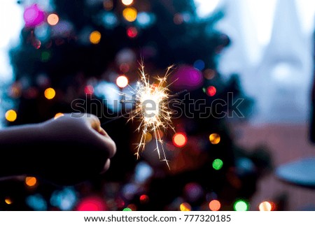 Burning  Bengal lights on Christmas tree light  background against defocused lights, close up

