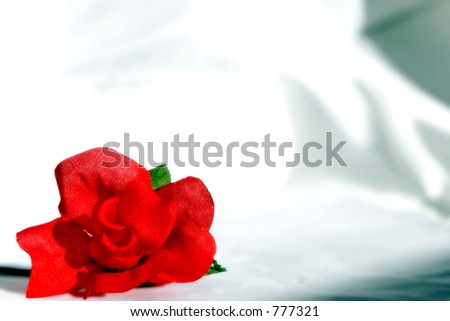A single red rose made of fabric - with romantic soft focus and saturated color.