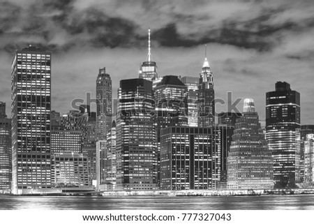 Black and white picture of New York City illuminated skyscrapers at night, USA.