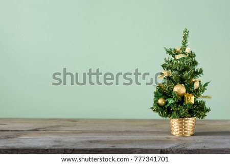 Christmas background. Little Christmas tree with decorations on a dark wooden table. Green background. Space for text. New Year's background.