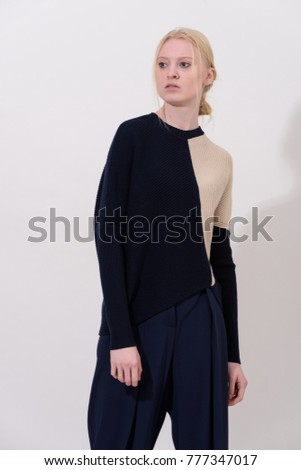 Fashion shooting in studio . Professional model of blonde, fashionable clothes and style, new collection. stylish look.
long pants and a sweater.
