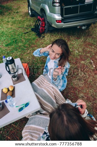 Back view of woman taking photo to happy young friend while having a breakfast in campsite