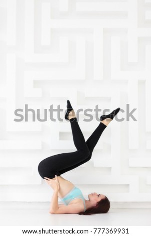 Side view of sporty young woman practicing advanced yoga, pilates, fitness over white wall background