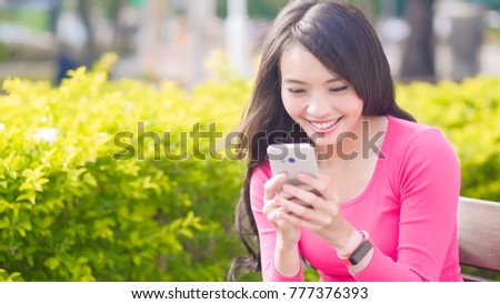 woman use phone and smile happily in the park