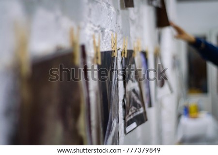 Photo cards fixed on the white wall by clothespin. Low depth of field
