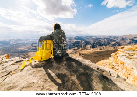 a young girl sits on the edge of a cliff and enjoys nature and mountains