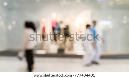 blurred image of people walk in the mall and the mannequins in the clothes shop 