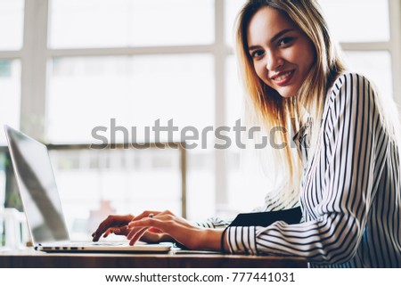Portrait of positive businesswoman smiling at camera while typing on keyboard of laptop computer in searching information on internet sources.Copy space area for your advertising text message