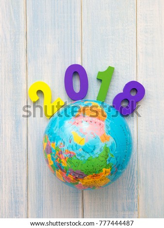 Colorful wooden 2018 round globe map on blue wooden table. New year holiday concept. Business world 2018.