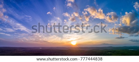 Panoramic sunset with light, puffy clouds in the sky overlooking summer New England forests. High resolution HDR panorama from drone Royalty-Free Stock Photo #777444838