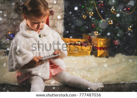 little girl making selfie on mobile phone near Christmas tree. Garland. New Year 2017. Fairy tale