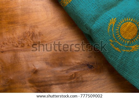Flag of Kazakhstan from rough fabric on a wooden background.