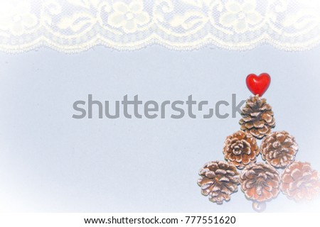 acorns formed into a triangle resembling a Christmas tree.  A red heart at the top to symbolize love. Blurred on purpose for a Christmas theme background