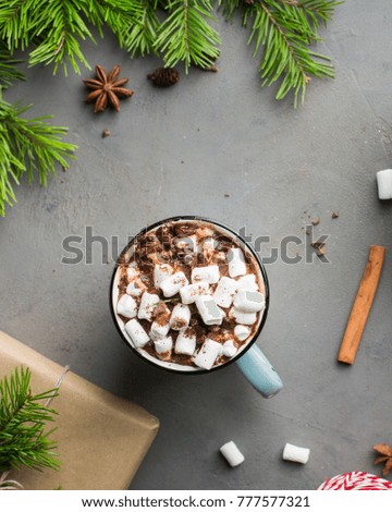 Mug of hot chocolate with marshmallow and cinnamon on gray concrete background with a Christmas tree, gifts. and red-white string (twine). Winter xmas holidays concept. Festive mood.Flat lay, top view