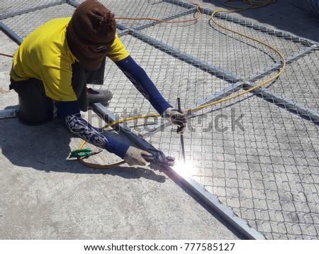 Worker is welding  for Steel wire tie in construction site. for Installation of barbed wire.Wear long gloves with stripes.concept for labor day Royalty-Free Stock Photo #777585127
