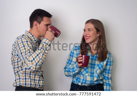 Young couple. Hipsters - positive woman and charming man drinking coffee in checkered shirts on white background
