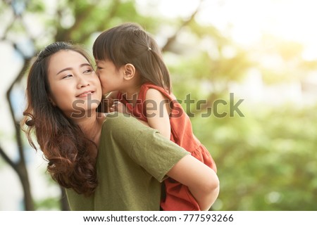 Girl kissing mother when she giving her piggyback ride