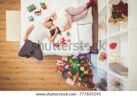 The kissing couple lay on the bed with gifts. view from above