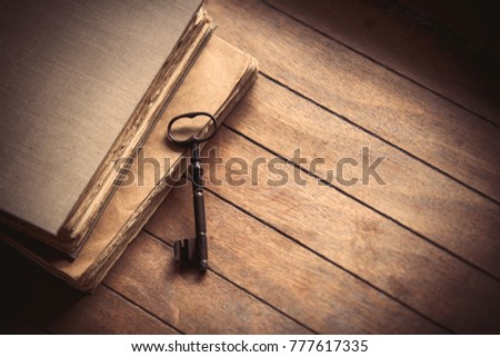 Vintage key and old books on wooden table. Photo in old image color style