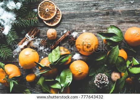 Traditional Christmas background with fir tree, tangerines, cinnamon and natural snow on wooden background. Top view, toned image
