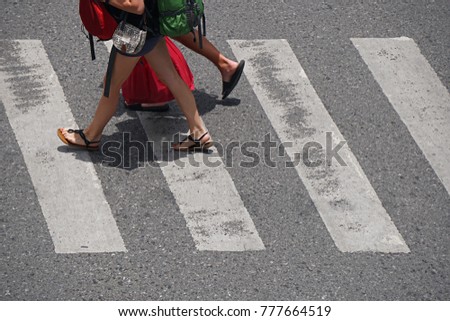 legs of tourist walking across the crosswalk at intersection street of city