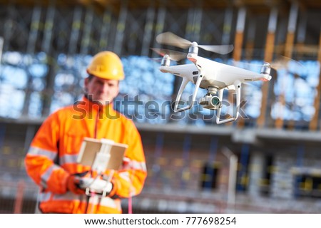 Construction worker piloting drone at building site. video surveillance or industrial inspection