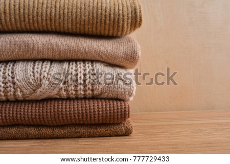 Stacked of knitted winter clothes , sweaters on wooden background
