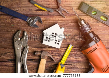 Wooden white house toy and construction tools on wooden background with copy space.Real estate concept, New house concept, Finance loan business concept, Repair maintenance concept Royalty-Free Stock Photo #777733183