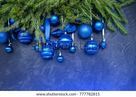 Christmas tree and blue balls with ribbon on dark blue background.