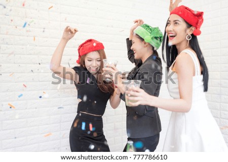 In Selective Focus of Group of beautiful young people in Party hats throwing colorful confetti and looking happy.