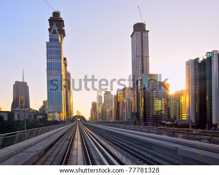 Modern city at sunset, metro overpass with rails, Dubai city in United Arab Emirates