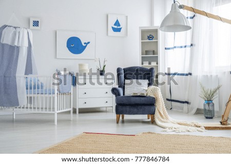 Brown carpet on the floor and pillow on navy blue armchair in baby's bedroom in marine style