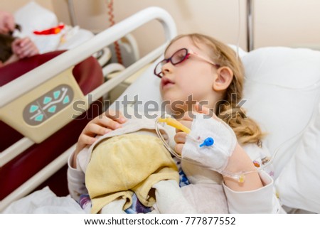 Little girl is receiving medication through intravenous fluid therapy in hospital bed, focus on drip.