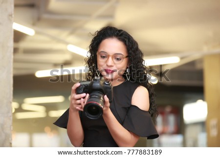 pretty dominican female photographer indoor, holding a camera